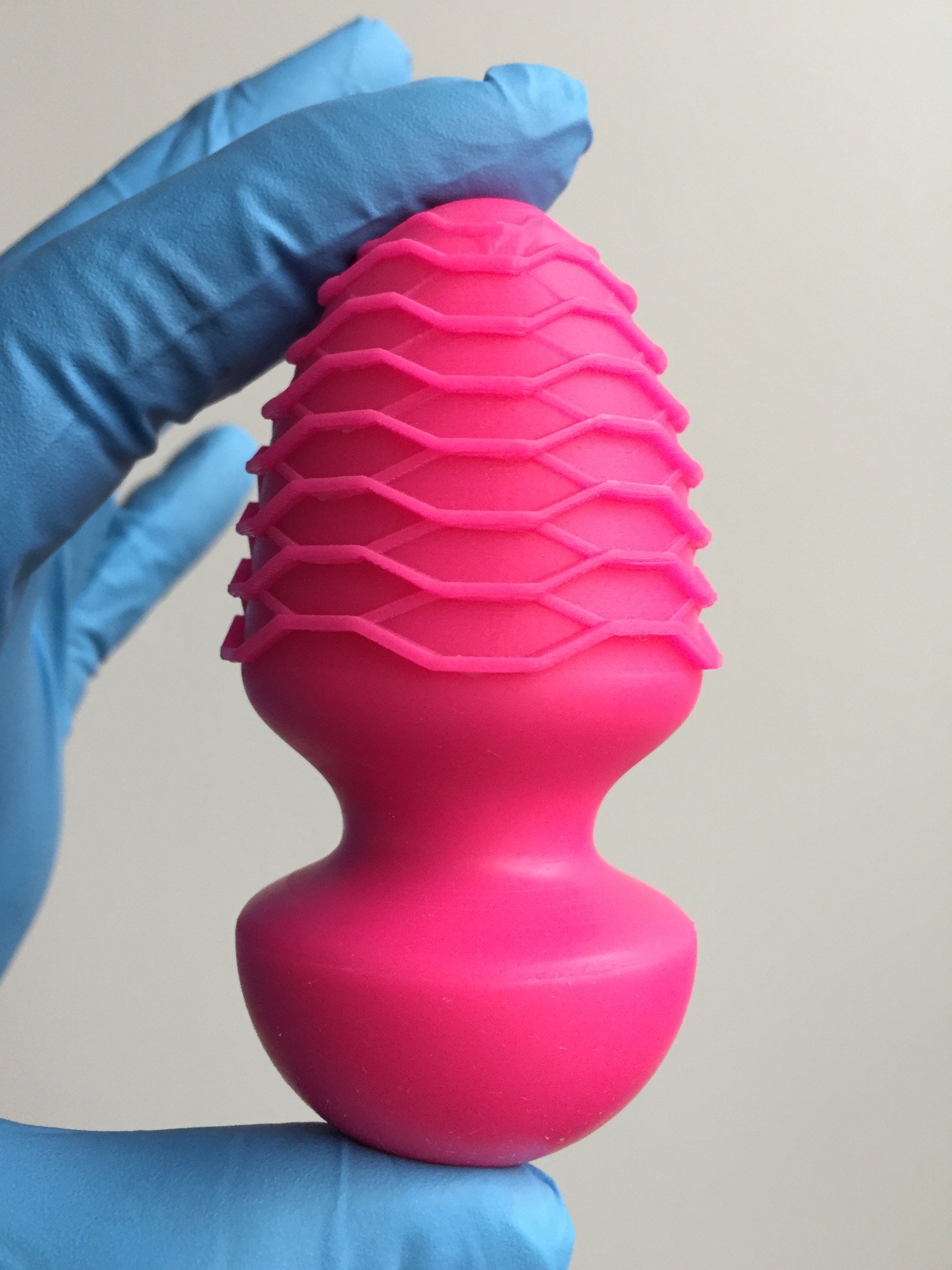 Photograph of the pink Vessel Plug held in a gloved hand
